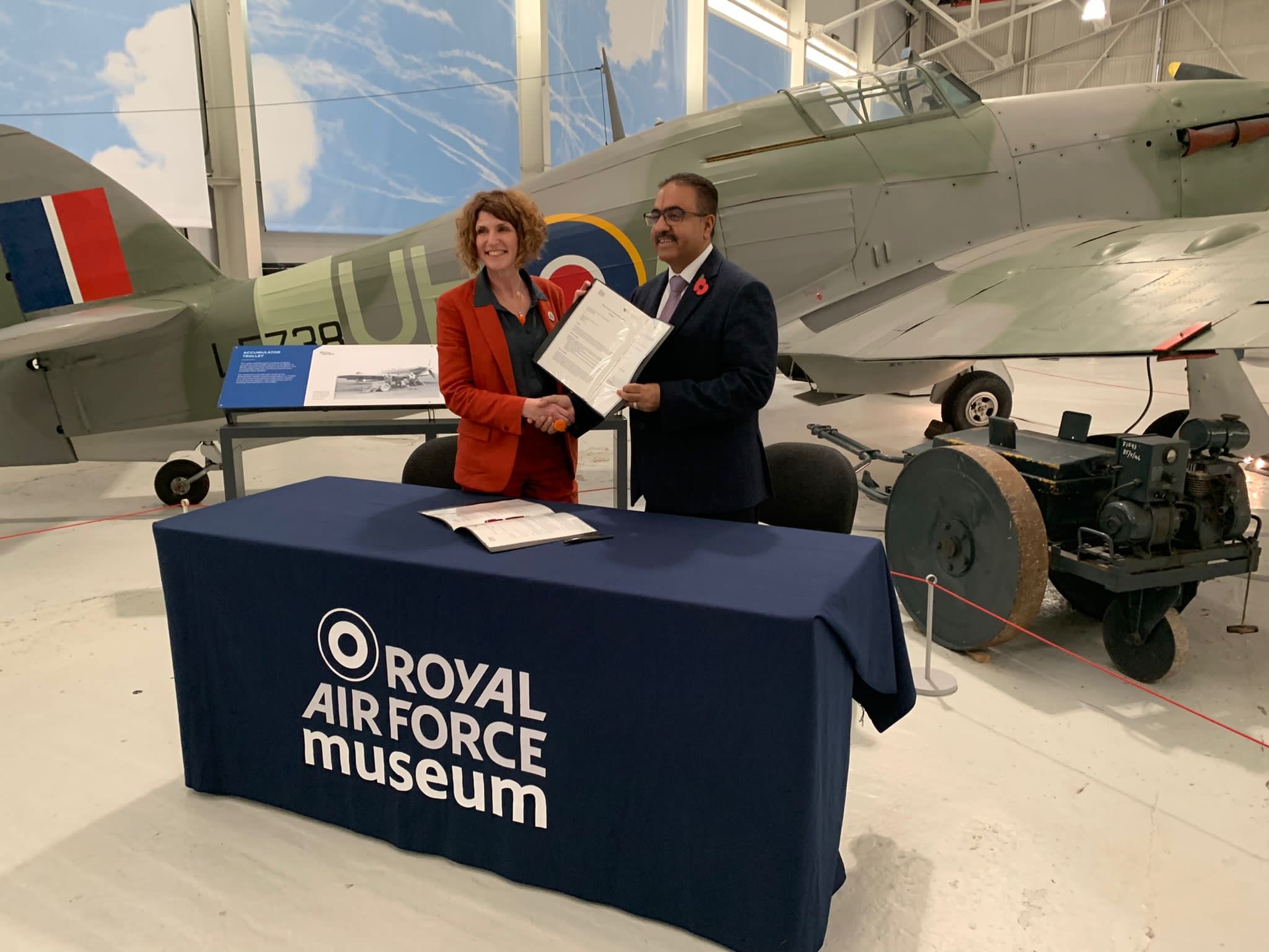 Two representatives holding the signed agreement between the RAF Museum Midlands and the Interfaith Council